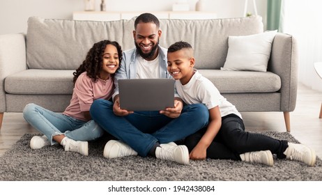 Happy african american family using laptop in living room - Shutterstock ID 1942438084