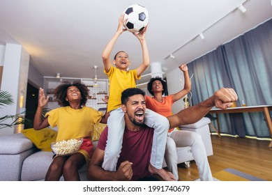 Happy African American Family Watching Soccer Match On Television In Living Room At Home.