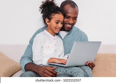 Happy African American Father And Daughter Using Laptop At Home