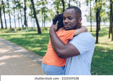 happy african american father holding and embracing adorable son in park - Shutterstock ID 1525559108