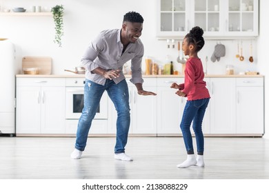 Happy African American Father And Little Daughter Dancing At Kitchen, Standing In Front Of Each Other, Making Crazy Moves, Happy Black Family Having Good Time Together At Home, Full Length, Copy Space