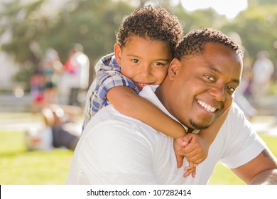 Happy African American Father and Mixed Race Son Playing Piggyback in the Park.