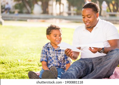 Happy African American Father and Mixed Race Son Playing with Paper Airplanes in the Park - Shutterstock ID 1900881118