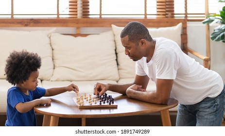 Happy African American Father And Son Playing Chess Game In Living Room Together. Family Activity And Leisure.