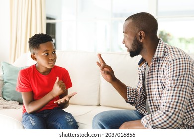 Happy african american father with son sitting on couch in living room talking sign language. father and son communicating without words. - Powered by Shutterstock