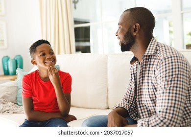 Happy african american father with son sitting on couch in living room talking sign language. father and son communicating without words. - Powered by Shutterstock