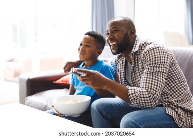 Happy African American Father And Son Sitting On Sofa, Watching Tv. Family Spending Time Together At Home.