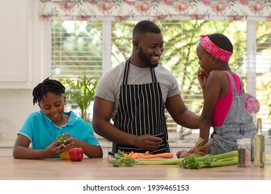 Happy African American Father Teaching Daughter And Son Cooking In The Kitchen. Staying At Home In Isolation During Quarantine Lockdown.