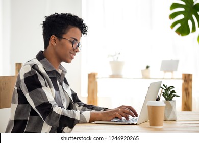 Happy African American Female Employee Work At Laptop In Loft Office, Smiling Black Woman Morning Routine With Coffee And Computer, Afro Lady In Glasses Browsing Internet Typing Message Or Email