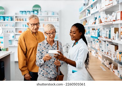 Happy African American female pharmacist advising senior couple buying vitamins in drugstore. - Powered by Shutterstock