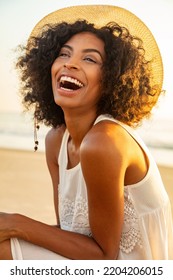 Happy African American Female Wearing Hat For UV Protection On Beach Laughing Enjoying Summer Fun On Luxury Vacation