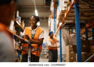Happy African American female worker writing notes while checking stock and communicating with coworker in storage room. - Powered by Shutterstock