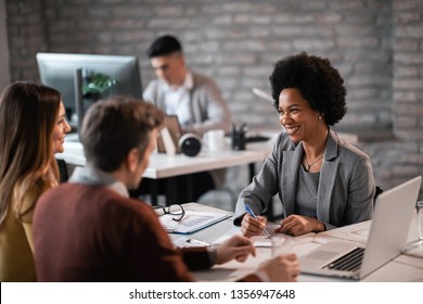 Happy African American financial advisor talking to a couple about their future investment during a meeting in the office. 