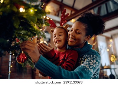 Happy African American girl  decorating Christmas tree with her mother at home.  - Powered by Shutterstock