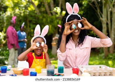 Happy African American Girl And Mother Playing With Easter Eggs While Family In Background. Unaltered, Lifestyle, Easter Day, Art, Celebration, Family, Cultures And Holiday Concept.