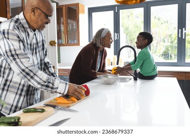 Happy african american grandmother and grandson washing vegetables in kitchen, slow motion. Food, cooking, home, family, togetherness, domestic life and lifestyle, unaltered. - Powered by Shutterstock