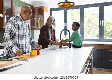 Happy african american grandmother and grandson washing vegetables in kitchen, slow motion. Food, cooking, home, family, togetherness, domestic life and lifestyle, unaltered. - Powered by Shutterstock