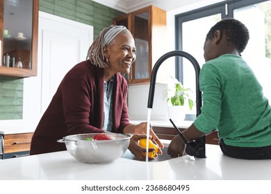 Happy african american grandmother and grandson washing vegetables in kitchen, slow motion. Food, cooking, home, family, togetherness, domestic life and lifestyle, unaltered. - Powered by Shutterstock