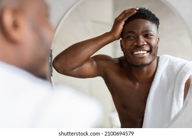 Happy African American Guy Touching Short Hair Looking At His New Haircut And Reflection In Mirror Standing Shirtless In Modern Bathroom At Home. Male Haircare Concept. Selective Focus