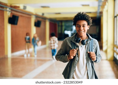 Happy African American high school student standing in hallway and looking at camera.