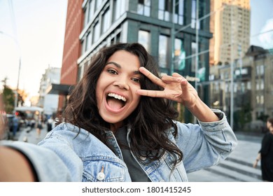 Happy African American hipster girl blogger influencer recording vlog holding looking at camera. Black teen travel vlogger influencer shooting video, streaming on urban city street, headshot. - Shutterstock ID 1801415245