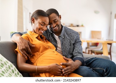 Happy african american husband and pregnant woman hugging belly. Smiling black man hugging happy pregnant wife sitting on sofa and holding tummy. Mature loving couple expecting their first baby. - Shutterstock ID 2143243897