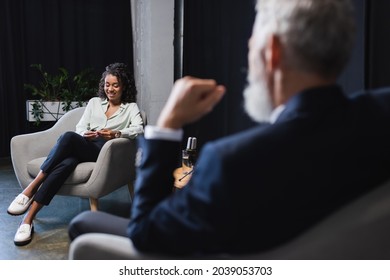 Happy African American Journalist Smiling Near Blurred Businessman During Talk Show