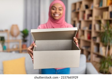 Happy african american lady holding open delivery box and stretching to camera, selective focus, closeup. Muslim woman unboxing parcel with ordered items