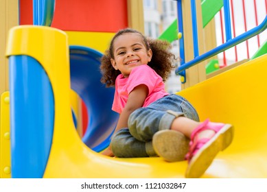 happy african american little kid sliding down from hill at playground  - Powered by Shutterstock