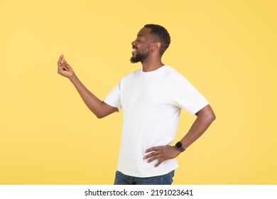 Happy African American Male Doing Finger Snap Gesture Clicking Fingers Posing Standing Over Yellow Studio Background, Looking Aside. It's Easy Concept