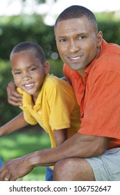 A Happy African American Man And Boy, Father And Son, Family Together Outside In Summer Sunshine