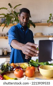 Happy African American Man Cooking Dinner In Kitchen, Using Tablet. Spending Quality Time At Home Alone.