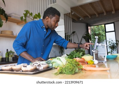 Happy African American Man Cooking Dinner In Kitchen, Using Tablet. Spending Quality Time At Home Alone.