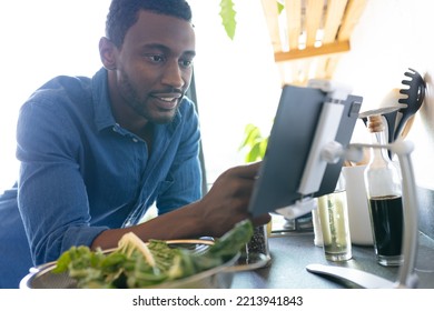 Happy African American Man Cooking Dinner In Kitchen, Using Tablet. Spending Quality Time At Home Alone.