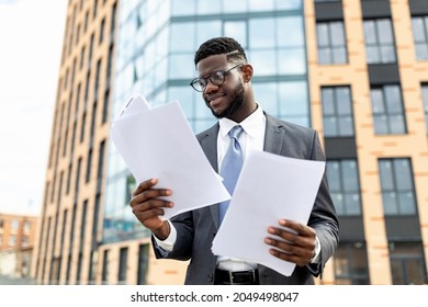 Happy African American Man In Formal Outfit Holding Documents Or CV, Getting Ready For Job Interview, Standing Outdoors Against Office Building, Copy Space