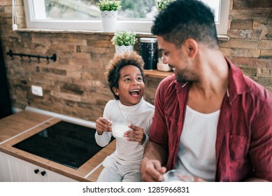 Happy African American Man And His Daughter Drinking Milk In The Morning.