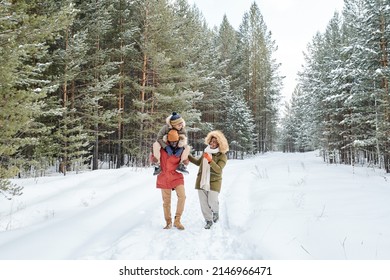 Happy African American man, his wife and son having stroll in fresh air on frosty winter day among coniferous trees covered with snow - Shutterstock ID 2146966471