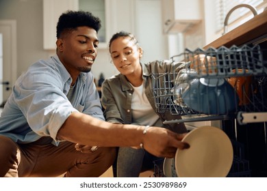 Happy African American man and his girlfriend using dishwasher int he kitchen.  - Powered by Shutterstock