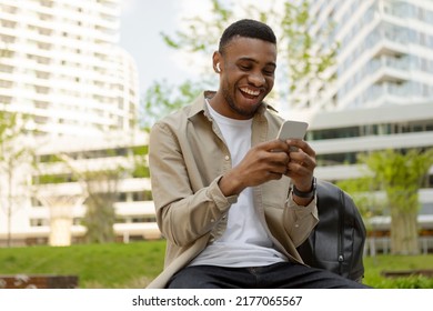 Happy african american man listening to a song on the street in headphones and with a mobile phone - Powered by Shutterstock