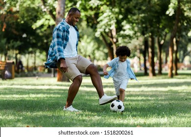 happy african american man playing football with curly son 