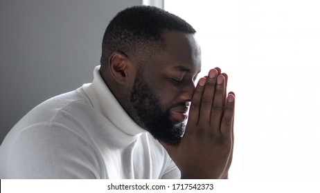 Happy african american man praying God, saying thanks for support and care

