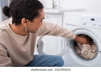 Happy African American Man Putting Clothes In Washing Machine