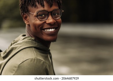 Happy african american man, wearing glasses looking at camera, cheerful black man posing outdoors in city