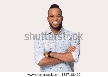 Happy african American man wearing shirt and glasses isolated on grey studio background stand posing with arms crossed, smiling biracial male in spectacles look at camera show white healthy teeth