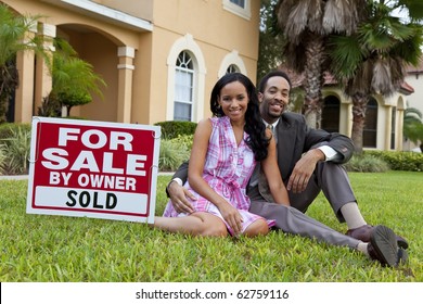 A Happy African American Man And Woman Couple Outside A Large House With A For Sale Sold Sign