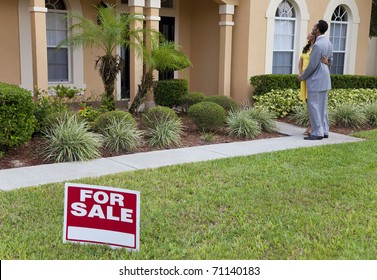 A Happy African American Man And Woman Couple House Hunting Outside A Large House With A For Sale Sign