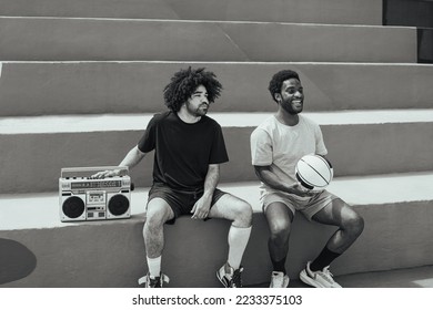 Happy African American men listening music inside basketball court with vintage boombox stereo - Urban street people lifestyle - Black and white editing - Shutterstock ID 2233375103