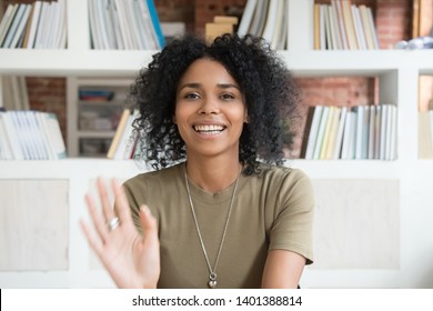 Happy african American millennial woman wave talk on webcam or having conversation, smiling positive black female blogger shoot record new blog or vlog, greeting say hello to followers audience