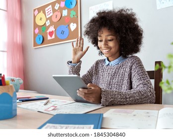 Happy african american mixed race kid girl waving hand talking with remote web teacher on social distance video conference call elearning virtual class on tablet. Children learning at home concept.