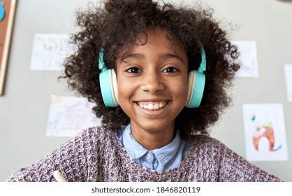 Happy African American Mixed Race Kid Child Girl Wearing Headphones Looking At Camera Or Web Cam Remote Distance Learning On Video Zoom Conference Call, Virtual Class, Headshot Close Up Face Portrait.